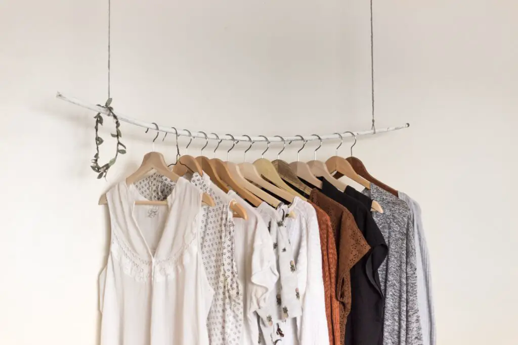 Neutral capsule wardrobe hanging on a branch clothesline