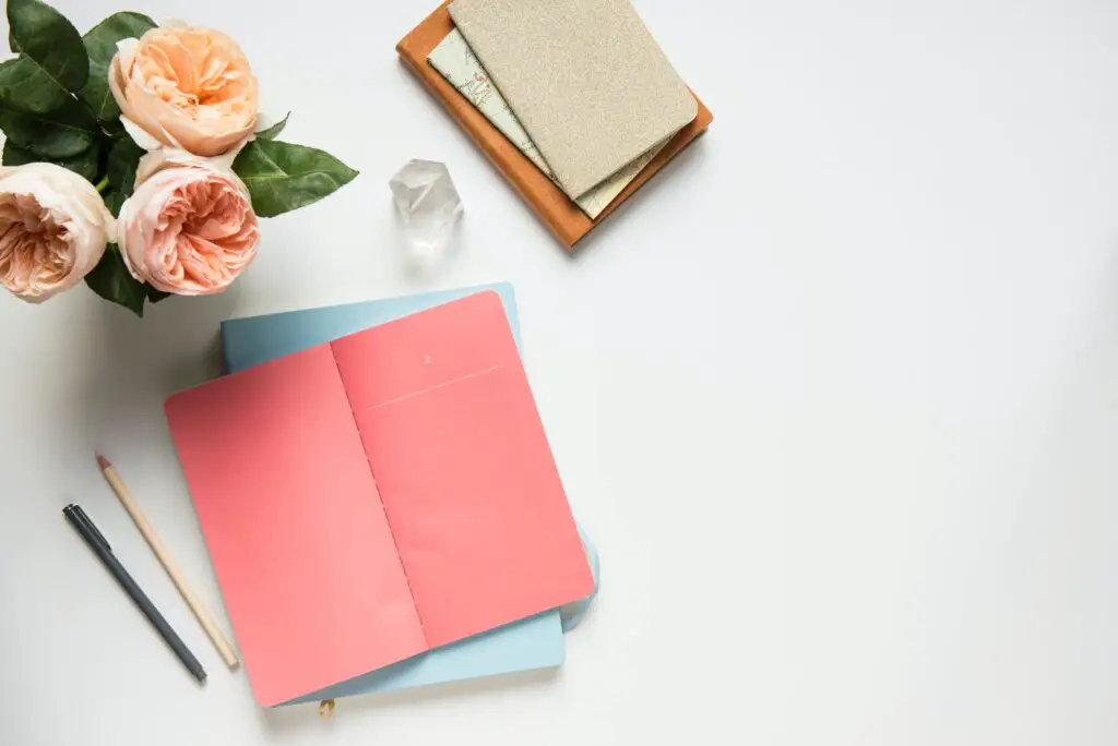 Bouquet of pink peonies and a pink journal for writing down positive midlife affirmations