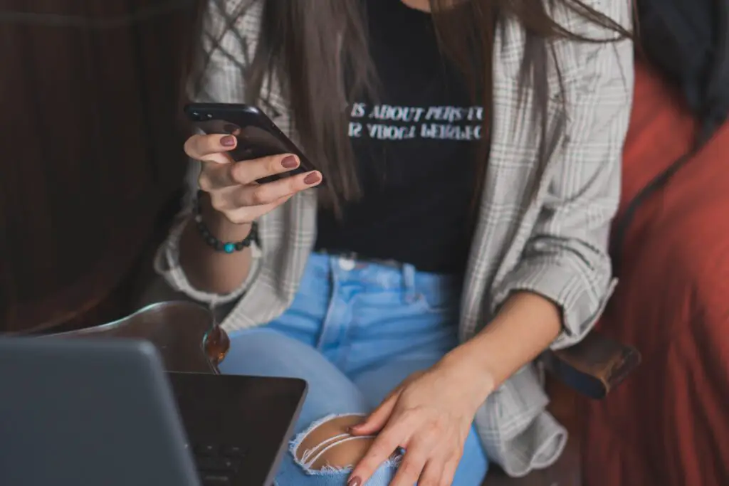 Woman checking her phone while working at her laptop