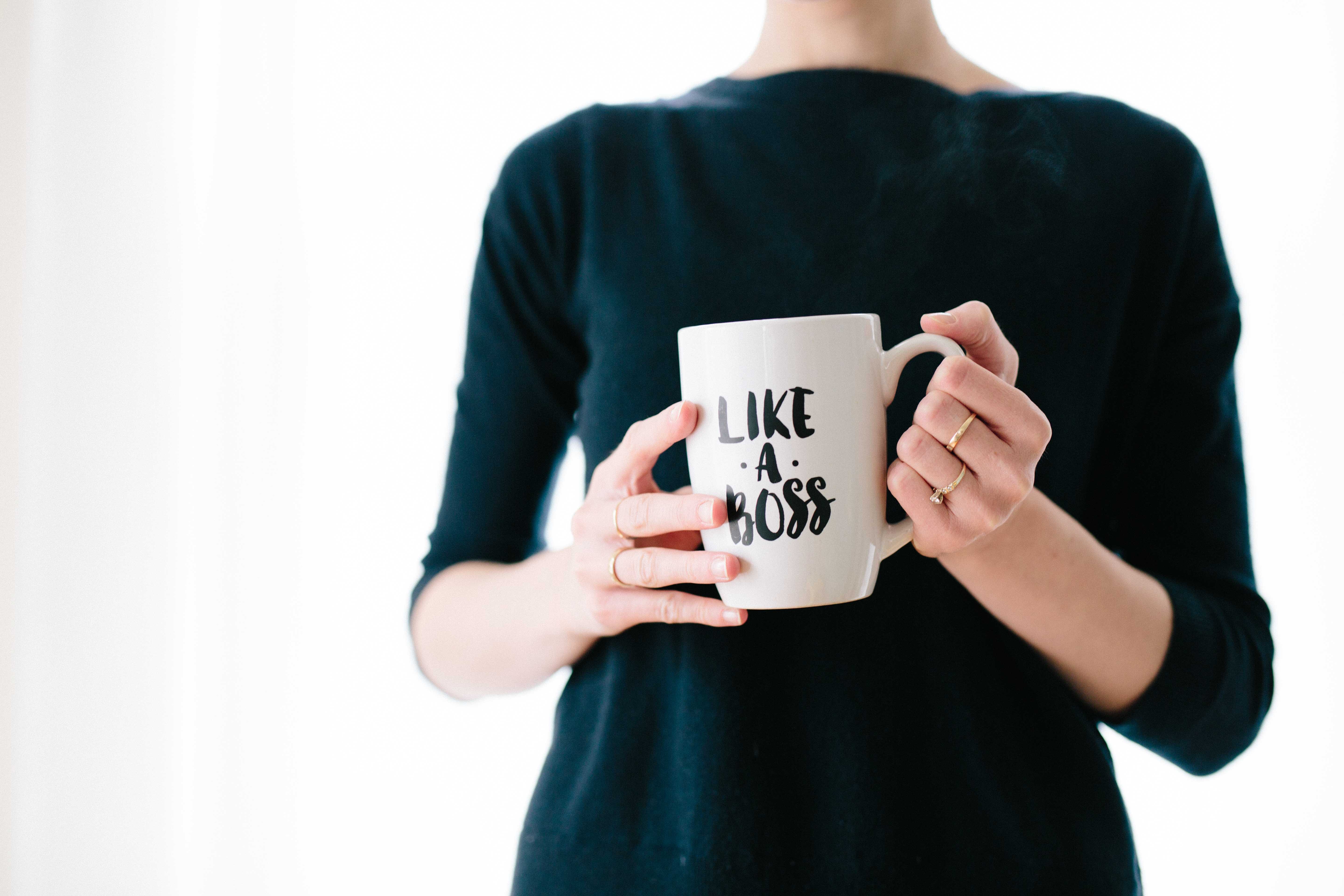 Woman holding a mug that reads Like a Boss. Working moms need routines to make work life balance easier.