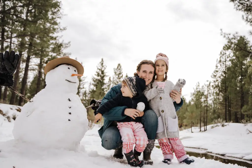 mom playing in the snow with her kids- essential holiday hacks for busy moms