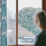 winter arc millenial woman looking out winter window